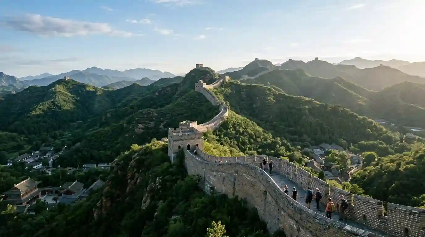 The Great Wall of China winding across green mountain ridges under a clear sky.